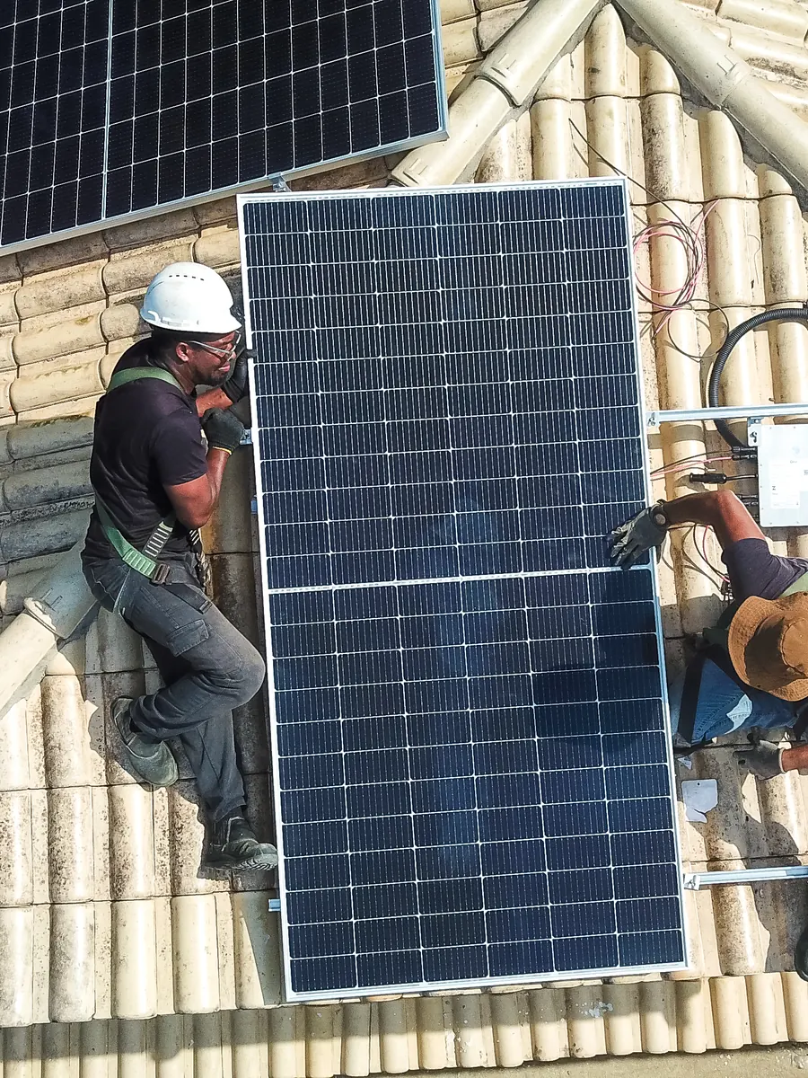 Dois técnicos da Meta Rio posicionando um módulo solar em telhado cerâmico